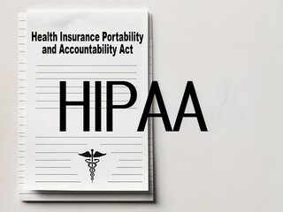 Paper on the left side has word text "Health Insurance Portability and Accountability Act" and "HIPAA" in bold large letters. There is a medical symbol, a caduceus, at the bottom of the paper.