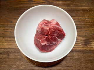 Fresh raw premium beef shank, ingredients for making dishes. Placed in a white ceramic bowl, on a wooden table.