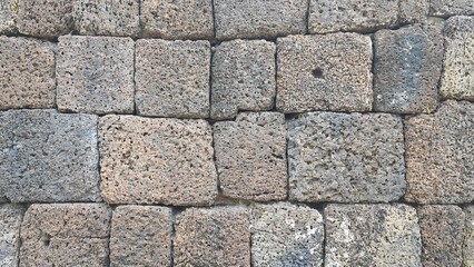 Ancient old brick stone texture pattern background. Ancient castle stone wall in Thailand, a fence made of large stones stacked in many layers.