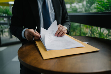 Businessman reviewing documents on a round table, with an envelope, showcasing professional work...