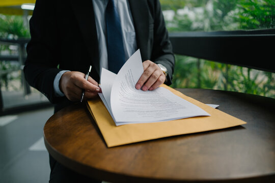 Businessman reviewing documents on a round table, with an envelope, showcasing professional work and attention to detail. Perfect for business, finance, and office concepts.