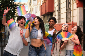 Group of young activists protesting for lgbt rights using megaphone and rainbow flags