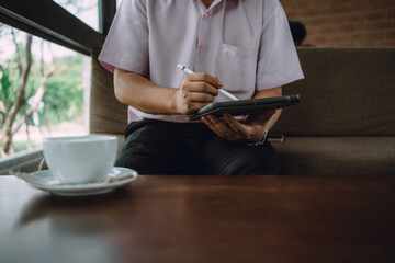 Man using a tablet with a stylus at a cafe table, alongside a cup of coffee, showcasing digital...