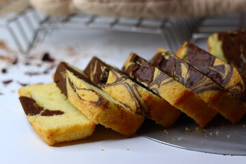 Slices of moist marble cake with chocolate and vanilla swirls, placed on a white surface.