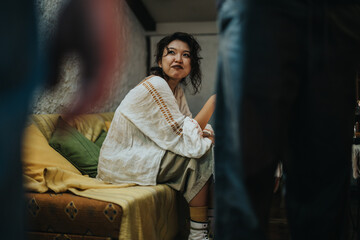 A cheerful woman in relaxed casual attire conversing on a cozy couch with friends, creating a warm and friendly indoor environment during a social gathering.