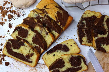 Slices of moist marble cake with chocolate and vanilla swirls, placed on a white surface.