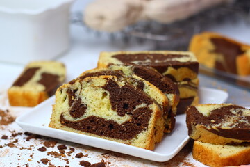 Slices of moist marble cake with chocolate and vanilla swirls, placed on a white surface.