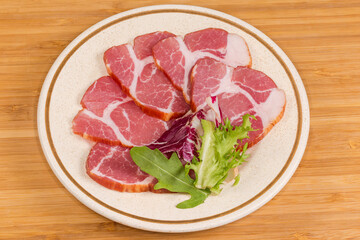 Slices of the dry-cured pork neck on a saucer