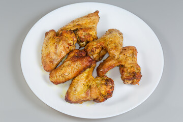 Baked chicken wings on the dish on a gray background