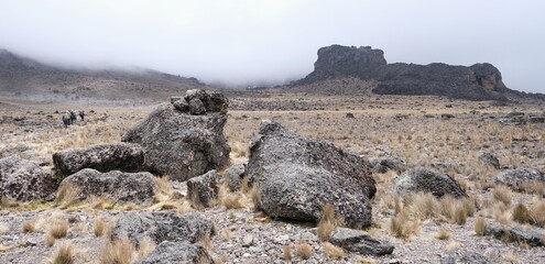 Kilimanjaro, Tanzania: Misty scenery of Lava Tower and silhouettes of trekking people. Machame Route, trail from Shira Camp to Barranco Camp. © Iwona