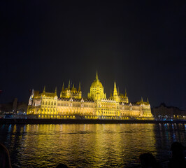 Obraz premium Illuminated Hungarian Parliament Building at night reflecting in the Danube River, Budapest cityscape with Gothic Revival architecture.
