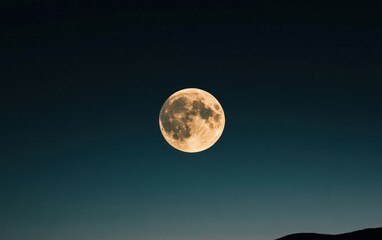 Large Yellow-Gold Full Moon in Dark Teal Night Sky over Silhouetted Mountains