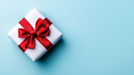White gift box with a red ribbon bow on a light blue background. Top view with copy space.