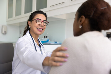 Happy positive senior doctor talking to young patient, sharing good news about examination result,...
