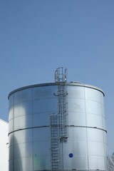 Metalowy zbiornik przeciwpożarowy z widoczną drabiną pionową prowadzącą na dach zbiornika