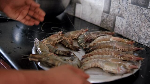 Chef skillfully arranging fresh tiger prawns on an elegant plate for culinary preparation