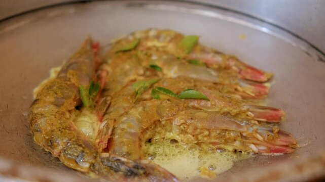 Chef skillfully frying succulent seasoned prawns in rich butter with aromatic herbs