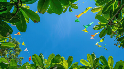 colorful pennant string decoration in green tree foliage on blue sky, summer party background template banner with copy space