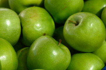 Fresh green apples gathered in a vibrant display at a local market during the sunny morning hours of early autumn