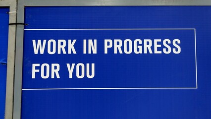 Work in progress message in English on a blue panel on metal structure.