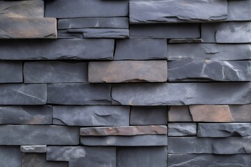 Close up view of a stacked stone wall featuring dark gray and brown hues, providing a textured and natural backdrop