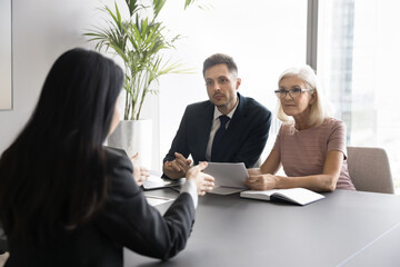 Rear back view female applicant passing job interview in company office, make speech, answers questions seated in front of attentive listening hr two HR managers. Headhunting, negotiations process