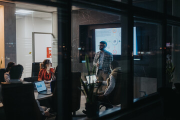 A multiracial team of business people collaborates on strategic ideas during a late-night meeting,...