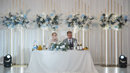 Newlyweds sharing intimate moment at decorated wedding table, surrounded by delicate flowers during romantic reception celebration