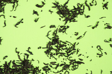 Loose black tea scattered on green background