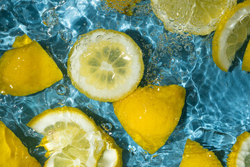 Juicy lemon background of halves and slices of fresh lemons in water.