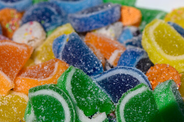 Colorful gummy candies arranged on a white surface create a visually delightful treat tempting...