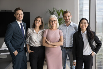 Happy young and mature, diverse professionals, company employee leaders looking at camera standing...