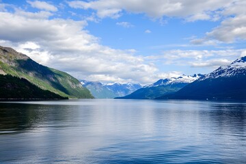 Serene lake surrounded by mountains, cloudy sky above, calm waters