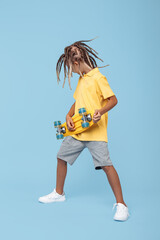 Gleeful little boy with african dreads listening music in headphones dancing over blue background.
