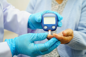 Asian doctor using digital glucose meter for check sample blood sugar level to treatment diabetes.