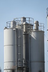 Silosy cementowni z widocznymi drabinami pionowymi