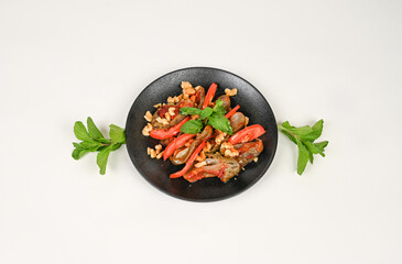 Makdous vibrant roasted eggplant salad with fresh tomatoes, crunchy walnuts, and aromatic mint leaves served on a black plate, beautifully garnished with sprigs of fresh herbs