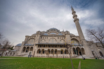 Magnificent exterior view of the historic S&uuml;leymaniye Mosque in Istanbul showcasing its grand Ottoman architecture, towering minaret, domes, and serene courtyard under a dramatic cloudy sky