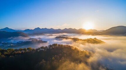 Fototapeta premium Breathtaking aerial view of misty mountains at sunrise with golden light illuminating the peaks, creating a serene and dramatic landscape in the morning mist.