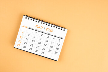 Top view of July 2025 desk calendar on yellow pastel background.