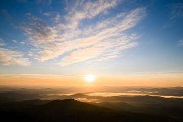 Fototapeta premium Sunrise view over hazy mountains and clouds in a beautiful sky