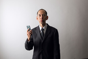 スマートフォンを持ったスーツ姿の中高年男性
