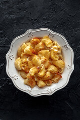 Mac and cheese, the classic pasta with macaroni and Cheddar cheese, baked in the oven, shot from the top on a black table