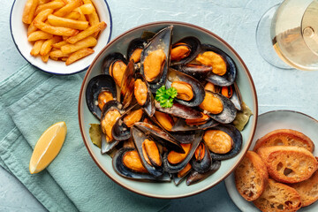 Mussels with French fries, white wine, lemon, and toasted bread, moules frites, overhead flat lay...