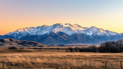 Sunset illuminates snow-capped mountains, grassy plains.