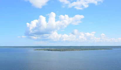 Fototapeta premium Serene lake under a bright blue sky with fluffy white clouds