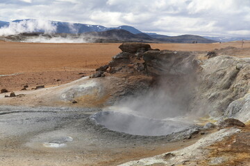 dark grey mud boiling and fuming in a geothermal mud pot in Namaskard geothermal area in Iceland