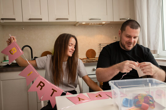 Happy Couple Preparing Birthday Decorations Together in Cozy Home Kitchen