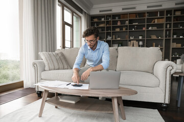 Managing household expenses. Busy gen z man homeowner businessman freelancer working from home...