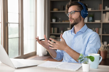 Online education. Confident male teacher in earphones explain learning material to class or pupil via virtual classroom app on notebook. Millennial student answer tutor question on video call meeting